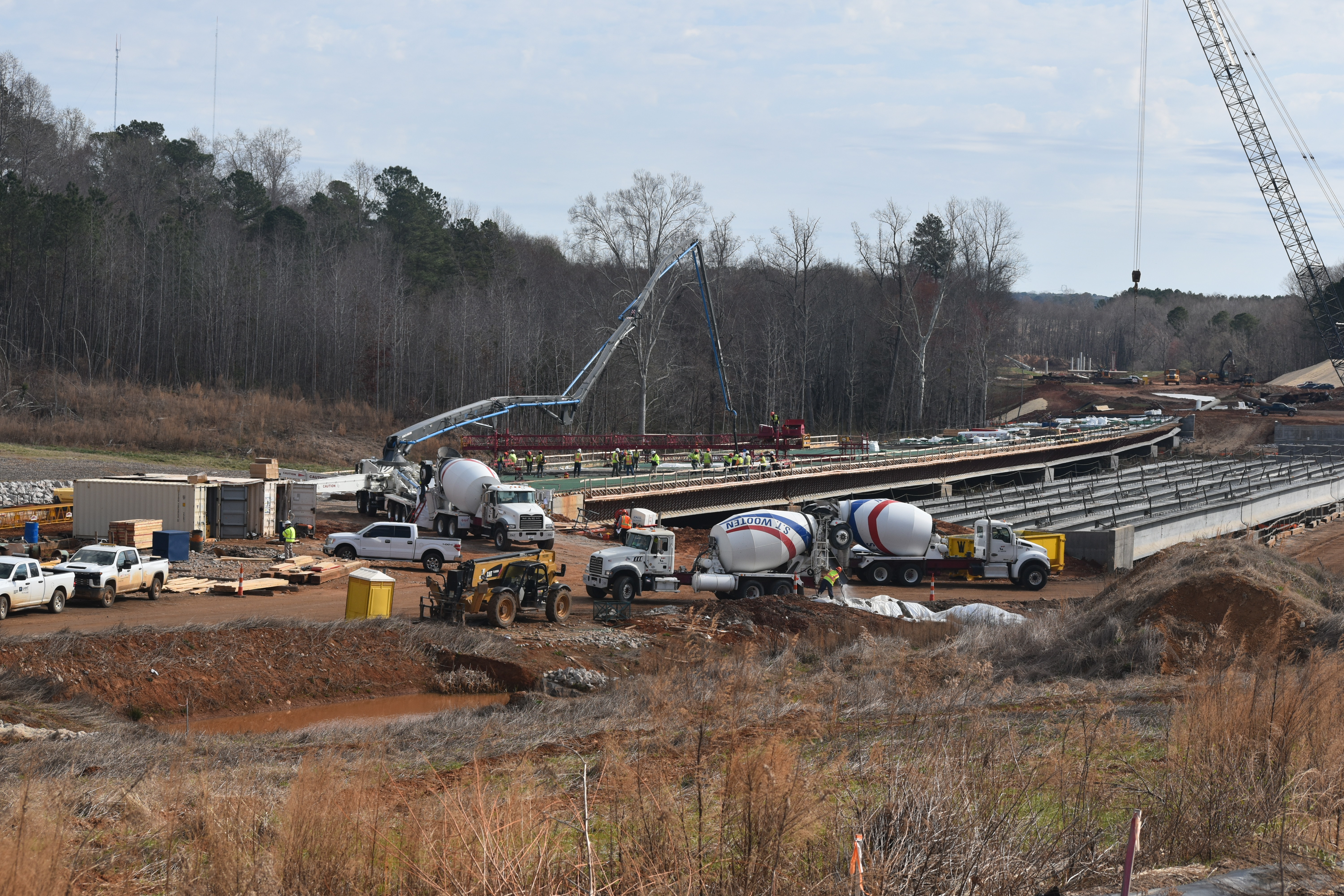 wide angle view of workers, trucks and highway project 